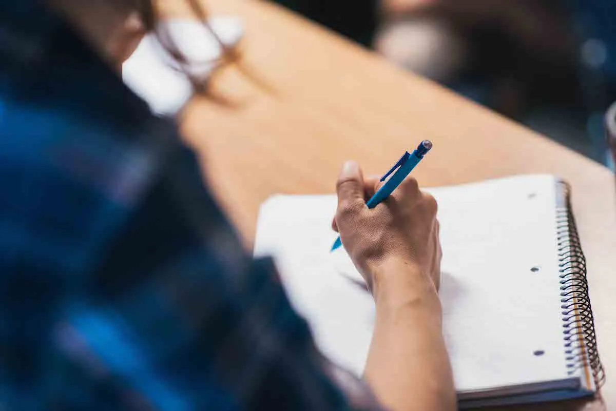 Image of a student writing in a notebook.