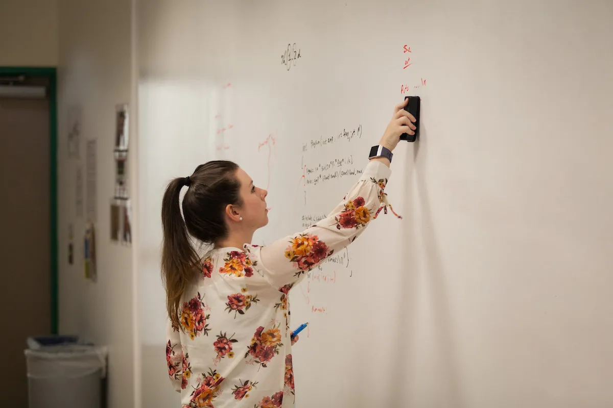 Professor writing on whiteboard.